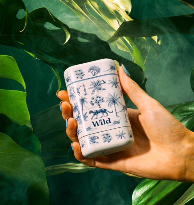 Wild refillable deodorant case held against jungle foliage